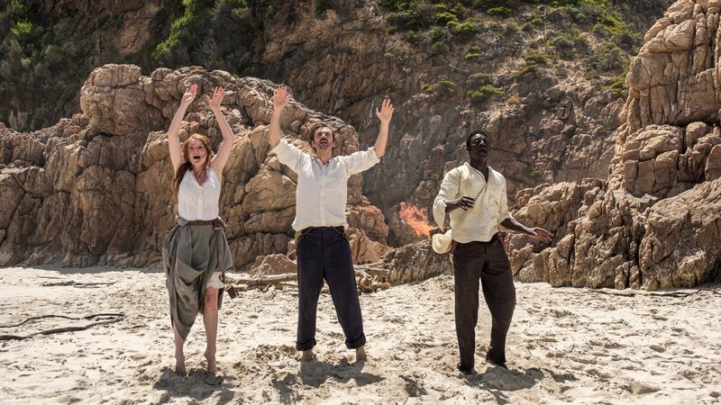 Das Floß, das sie gebaut haben, verbrennen sie wieder, um den kranken Passepartout am Feuer zu wärmen. Der Rauch macht ein Schiff, das in der Ferne vorbei fährt, auf Phileas Fogg (David Tennant, M.), Abigail Fix (Leonie Benesch, l.) und Passepartout (Ibrahim Koma, r.) aufmerksam. – Bild: ZDF und Graham Bartholomew