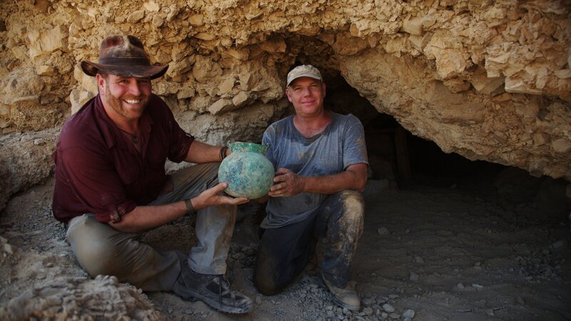 Josh Gates und Dr. Oren Gutfeld von der Hebräischen Universität Jerusalem mit einem hellenistischen Fund aus dem dritten Jahrhundert v. Chr. in der Höhle 53 in Qumran, Westjordanland. – Bild: Discovery Communications