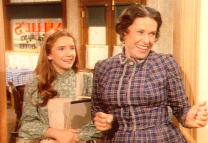 Mrs. Oleson (Katherine MacGregor, r.) und Laura (Melissa Gilbert, l.) begrüßen Almanzo, den jüngeren Bruder der neuen Lehrerin. Laura ist von dem jungen Mann sichtlich angetan … – Bild: Sat.1 Gold