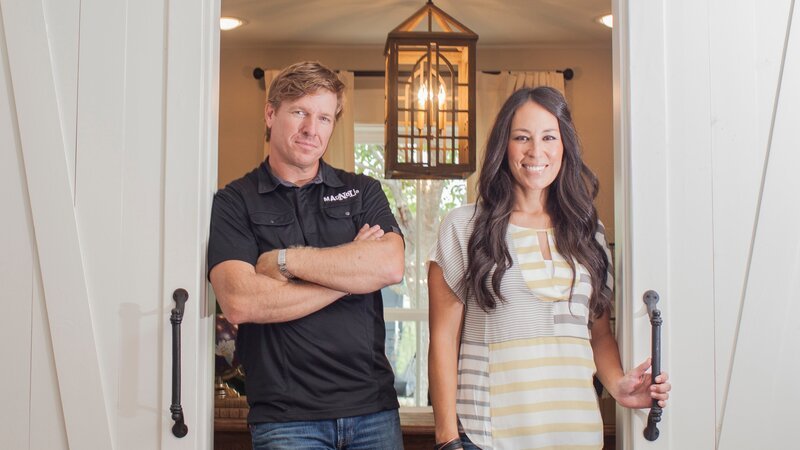 Hosts Chip and Joanna Gaines stand at the sliding doors to Ermoian’s newly remodeled office, as seen on Fixer Upper. – Bild: Jennifer Boomer/​Getty Images /​ HGTV /​ Scripps Networks, LLC.