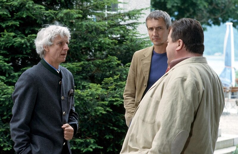 Nach dem Mord an einer seiner Angestellten hat Hotelier Ferdinand Buxner (Mathieu Carriere, l.) plötzlich panische Angst, dass der Mörder es nun auf ihn abgesehen haben könnte. Für die beiden Rosenheim-Cops Korbinian Hofer (Joseph Hannesschläger, re.) und Ulrich Satori (Markus Böker, mi.) kein leichter Fall. – Bild: ORF/​Christian A. Rieger