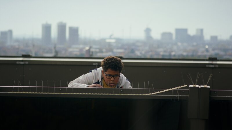 Kofi (Mathieu Noël) auf Beobachtungsposten auf dem Dach der Bank. – Bild: NDR/​Letterbox