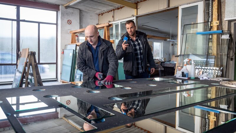 Lars Pöhlmann (Dominic Boeer, r.) stattet Matthias Becker (Matthias Hörnke, l.) einen Besuch in seiner Glaserei ab. Der Mann ist von seiner Frau Daniela Becker gerade erst für den viel jüngeren Jonas Pentke verlassen worden. Und nun ist Jonas Pentke tot! Hat sich Matthias Becker Hoffnungen gemacht, seine Frau wieder zu gewinnen? Hat er den neuen Lebensgefährten seiner Frau umgebracht? – Bild: ZDF und Marc Meyerbröker