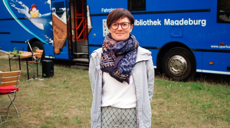 Doreen Potrzeba, Leiterin der Fahrbibliothek, vor dem Bus, der täglich durch Magdeburg fährt. – Bild: MDR