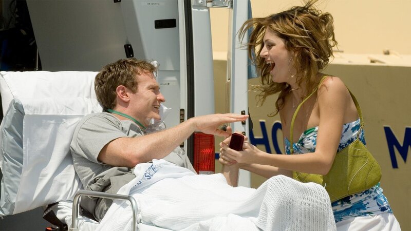 Chefo (Joshua Lawson) hat den Stich der Irukandji-Qualle überlebt. An Land macht er seiner Verlobten () einen Antrag – Bild: AXN Black