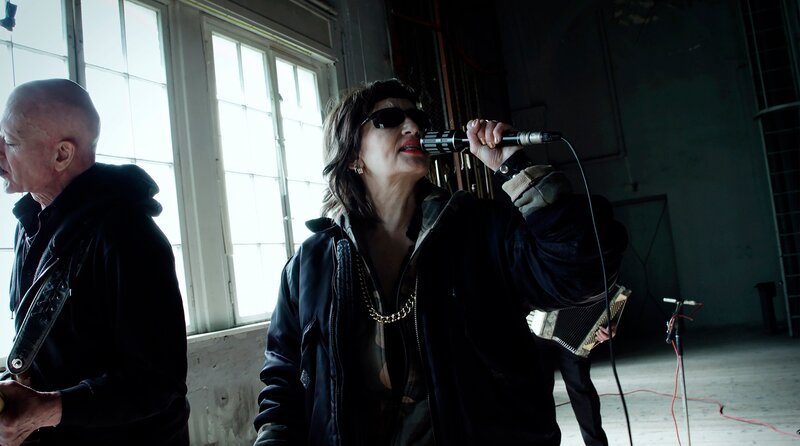 Wünsdorf ist ein ehemaliger Militärstandort in Brandenburg. Von hier aus wurden der Erste und der Zweite Weltkrieg geplant – und nach dem Krieg der „Kalte Krieg“. 1994 zog die russische Armee ab. Der Architekt, Stadtplaner und Pionier für ökologischen Städtebau Ekhart Hahn engagiert sich für eine zukunftsfähige Transformation des Ortes. Während der Dreharbeiten bricht der Krieg in der Ukraine aus. – Mona Mur & Band (En Esch) – Bild: rbb/​Filmgalerie 451