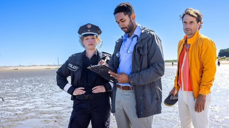 Auf Heimatbesuch joggt Tim (Oliver Mommsen, re.) zufällig an einem Tatort vorbei, wo er Wiebke (Antonia Bill, li.) und Dr. Müller (Benito Bause, Mitte) ordentlich auf die Nerven geht. – Bild: Romance TV