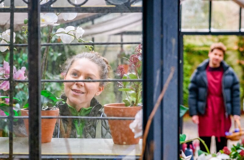 Kilian (Anthony Paul, r.) ertappt Fanny (Johanna Graen, l.) im Gespräch mit ihren Pflanzen. – Bild: ORF/​ARD/​Christof Arnold