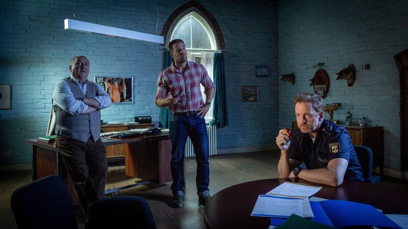 Revierchef Reuter (Udo Kroschwald, l.), Kommissar Pöhlmann (Dominic Boeer, M.) und Polizeihauptmeister Timmermann (Mathias Junge, r.) tappen im Dunkeln. Nicht nur, dass sie mit Hochdruck einen Mörder im Umfeld von Preppern und Verschwörungstheoretikern suchen – auch mit einem Stromausfall müssen sich die Kollegen der SOKO diesmal rumschlagen. – Bild: ZDF /​ Meyerbroeker