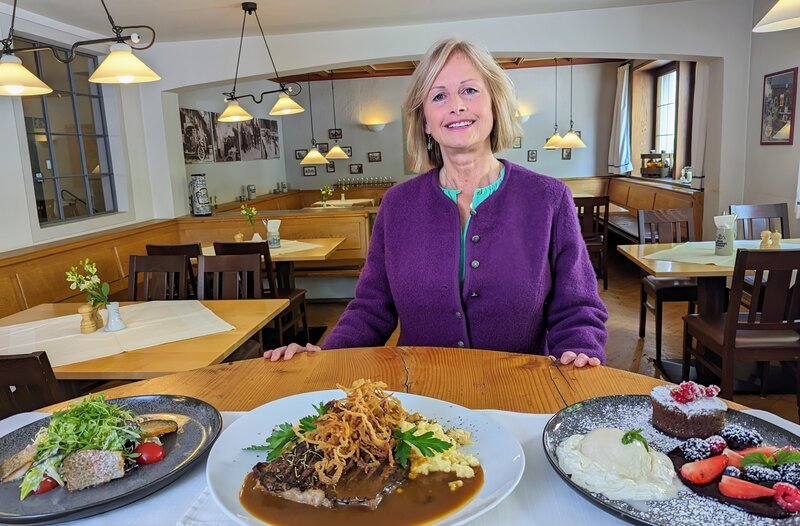 Wirtin Sonja Zinth vor dem Menü des Tages. – Bild: BR/​Bewegte Zeiten Filmproduktion GmbH/​Carsten Frank