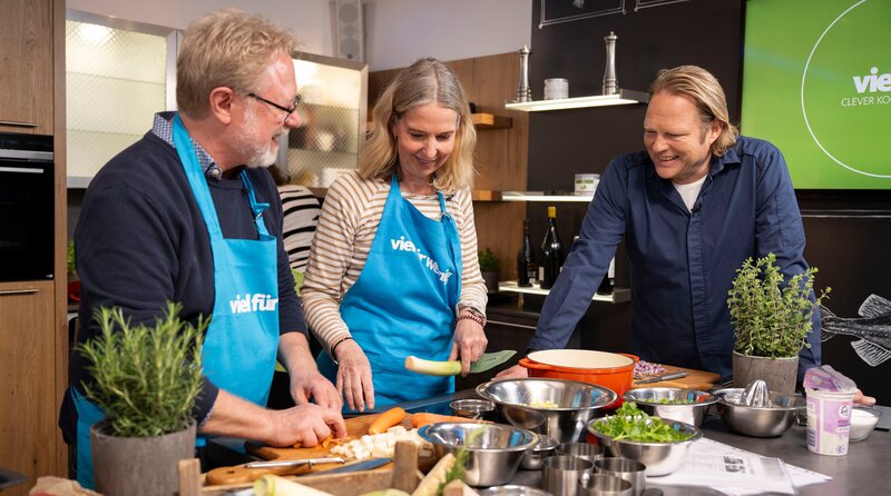 Dass das Kochen auch Spaß macht, ist Björn Freitag (r.) wichtig. Manchmal ist es aber auch schön, wenn man beim Schnippeln nicht mithelfen muss. – Bild: WDR/​solis TV/​Melanie Grande