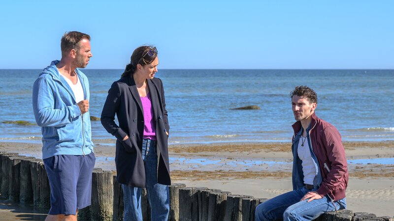 Das Strandcafé von Florian Albertsen (Martin Bruchmann, r.) liegt direkt neben dem Strandkorbverleih der toten Influencerin. Lars Pöhlmann (Dominic Boeer, l.) und Karoline Joost (Nike Fuhrmann, M.) wollen wissen, in welcher Beziehung er zu der jungen Frau stand. – Bild: Marc Meyerbröker /​ ZDF