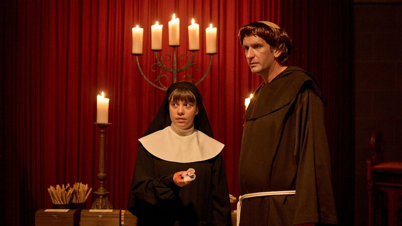 Jenny (Eva Bühnen, l.) zeigt Heino (Sebastian Schwarz, r.), wie sie die Mordwaffe provisorisch gesichert hat. Für ein Krimidinner sind sie als Nonne und Mönch verkleidet. – Bild: WDR Mediagroup GmbH