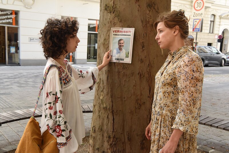 Kathi Kämmerer (Laura Diego, l.) bemerkt, dass ihre Mutter Marie Kämmerer (Martina Ebm, r.) eine Vermisstenanzeige ihres Vaters aufhängt. – Bild: ZDF und Hubert MICAN