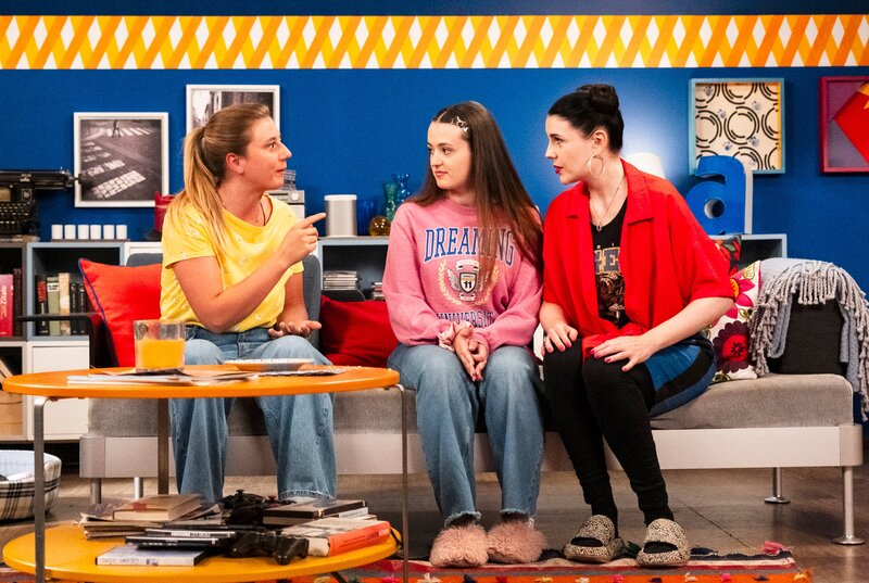 Sarah will Maja überzeugen, dass der Alltag lustiger ist als Sitcom-Serien. Von links: Sarah (Sophie Reiml), Maja (Godiva Adela), Tina (Anita Eichhorn). Weiteres Bildmaterial finden Sie unter www.br-foto.de. – Bild: BR/​Lena Semmelroggen