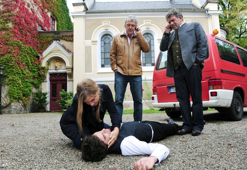 Konstantin (Moritz Tittel, liegend) ist durch Andrés (Joachim Lätsch, 2.v.r. mit Michele Oliveri, r.) Schuld verunglückt – Theresa (Ines Lutz, l.) fürchtet um sein Leben. – Bild: ARD/​Ann Paur