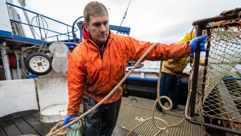 Clark holding coiled line and pot on launcher. – Bild: Warner Bros. Discovery, Inc. or its subsidiaries and affiliates