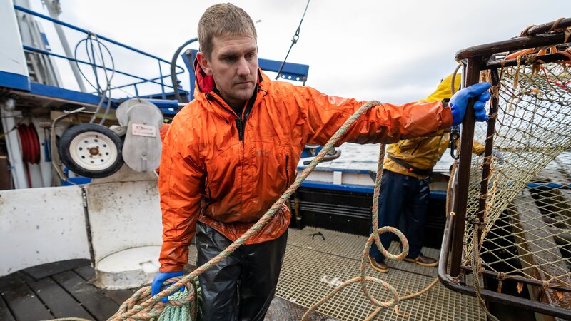 Clark holding coiled line and pot on launcher. – Bild: Warner Bros. Discovery, Inc. or its subsidiaries and affiliates