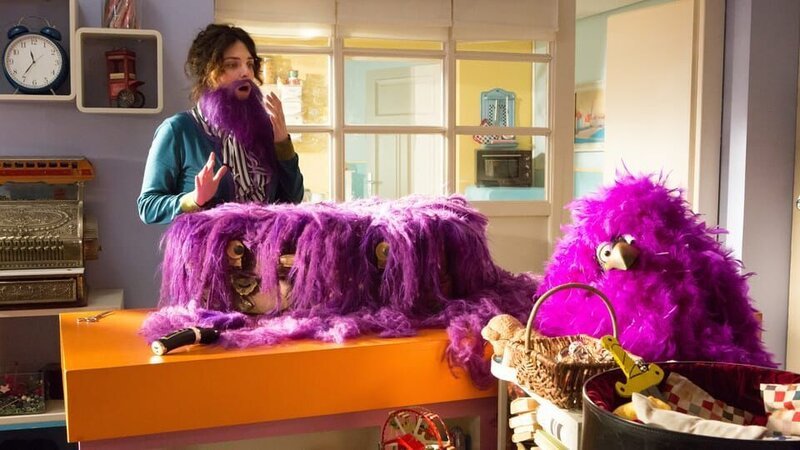 Der Koffer (Thomas Rohloff) liegt überwuchert von lila Haaren auf dem Tresen und schaut erschrocken zur Seite. – Bild: ZDF/​Zia Ziarno