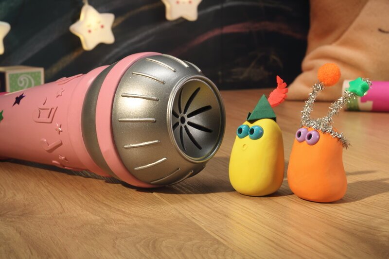 Guetnachtgschichtli - Die Mini Boings - Musigstars und Umerolle; Staffel 2, Folge 3; Zwei Mini Boings mit dekorierten Köpfen, die auf ein grosses pink-silbernes Mikrofon blicken. – Bild: SRF/Aardman Guetnachtgschichtli - Die Mini Boings - Musigstars und Umerolle; Staffel 2, Folge 3; Zwei Mini Boings mit dekorierten Köpfen, die auf ein grosses pink-silbernes Mikrofon blicken. – Bild: SRF/Aardman