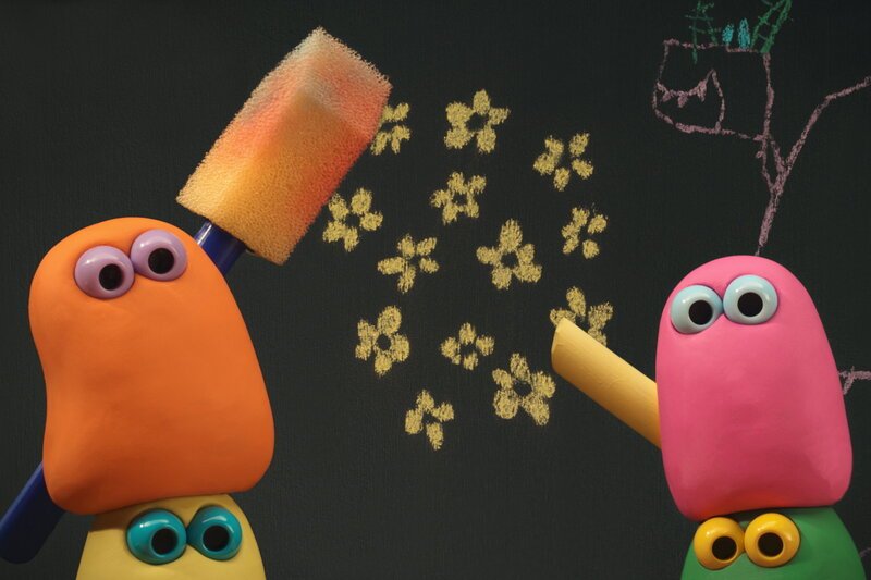 Guetnachtgschichtli — Die Mini Boings: Schatzsuechi und Zeichne; Staffel 2, Folge 4. Zwei Mini Boings zeichnen auf der Tafel. Der linke (orange) hält einen Schwammpinsel, der rechte (pink) ein gelbes Stück Kreide. – Bild: SRF/Aardman Guetnachtgschichtli — Die Mini Boings: Schatzsuechi und Zeichne; Staffel 2, Folge 4. Zwei Mini Boings zeichnen auf der Tafel. Der linke (orange) hält einen Schwammpinsel, der rechte (pink) ein gelbes Stück Kreide. – Bild: SRF/Aardman