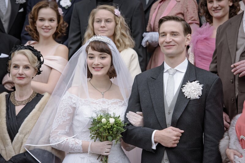 Da ist die Welt noch in Ordnung: Das Brautpaar Helga (Maria Ehrich) und Wolfgang von Boost (August Wittgenstein) beim gemeinsamen Foto mit ihren Hochzeitsgästen. – Bild: ZDF und Stefan Erhard