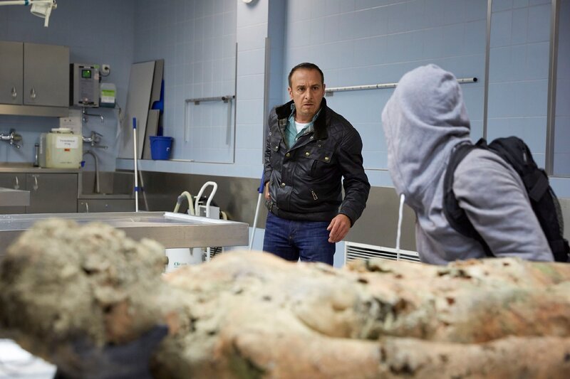 Semir (Erdogan Atalay, l.) überrascht im Seziersaal einen maskierten Unbekannten. – Bild: TVNOW /​ Guido Engels