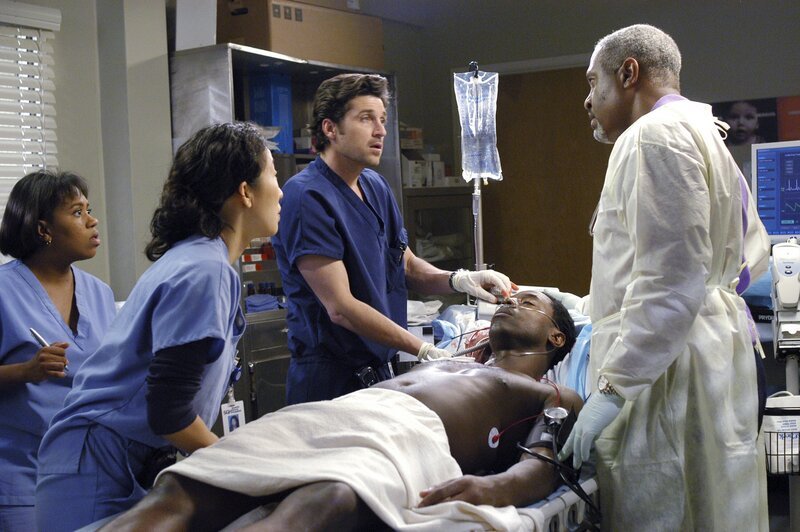 Burke (Isaiah Washington, liegend) hat viel Blut verloren, zeigt aber Lähmungserscheinungen; Derek (Patrick Dempsey, 3.v.l.) steht vor der Aufgabe, eine hochriskante OP durchzuführen. Dr. Webber (James Pickens Jr., r.), Dr. Bailey (Chandra Wilson, l.) und Cristina (Sandra Oh, 2.v.l.) sind einverstanden. – Bild: ABC, INC. /​ Gale Adler