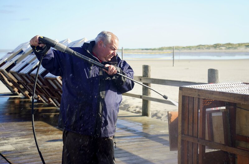 Mit dem Hochdruckreiniger gegen Salz und Sand: Heinz-Dieter Hecke macht die Strandkörbe von St. Peter-Ording winterfest. – Bild: NDR