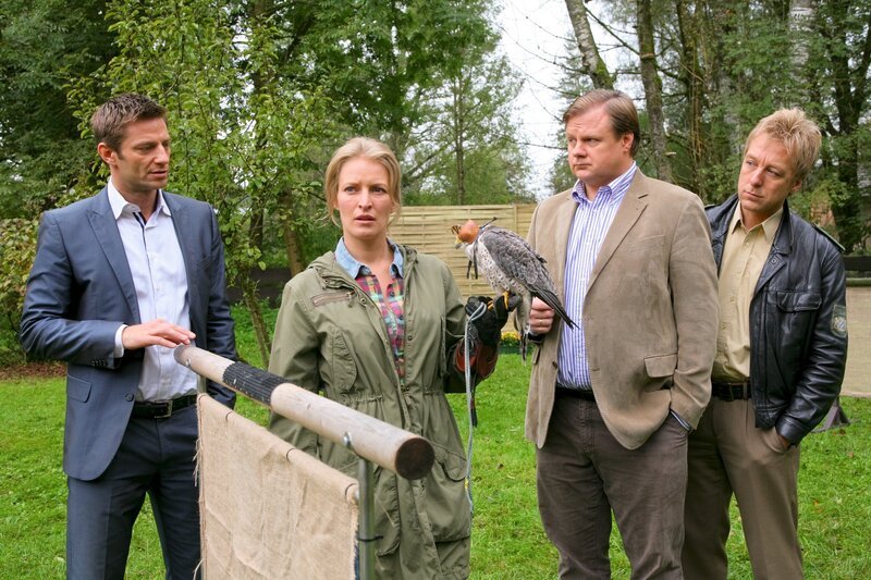 Die Rosenheimer Ermittler Hansen (Igor Jeftic, l.), Hartl (Michael A. Grimm, 2.v.r.) und Mohr (Max Müller, r.) recherchieren bei Sandra Holzinger (Stefanie von Poser, 2.v.l.). – Bild: ZDF/​Christian A. Rieger