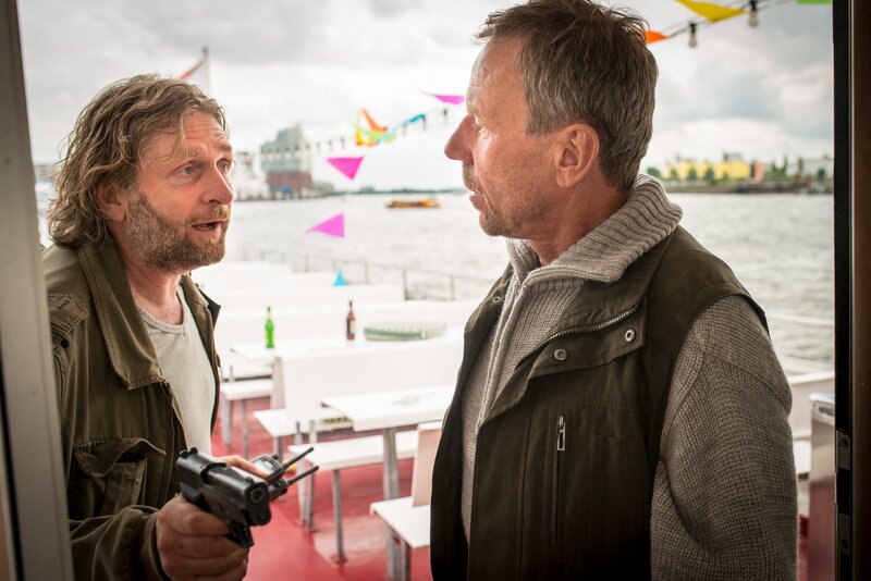 Malte Lampert (Jörg Witte, l.) hat Tarik seine Dienstwaffe abgenommen und verlangt nun von Schiffsführer Uwe Bachmann (Jörg Pose, r.), eine Hafenrundfahrt zu machen. Lampert will die entführten Polizisten als Druckmittel benutzen, um ein Gespräch mit seinem Sohn zu erpressen. – Bild: ZDF und Boris Laewen