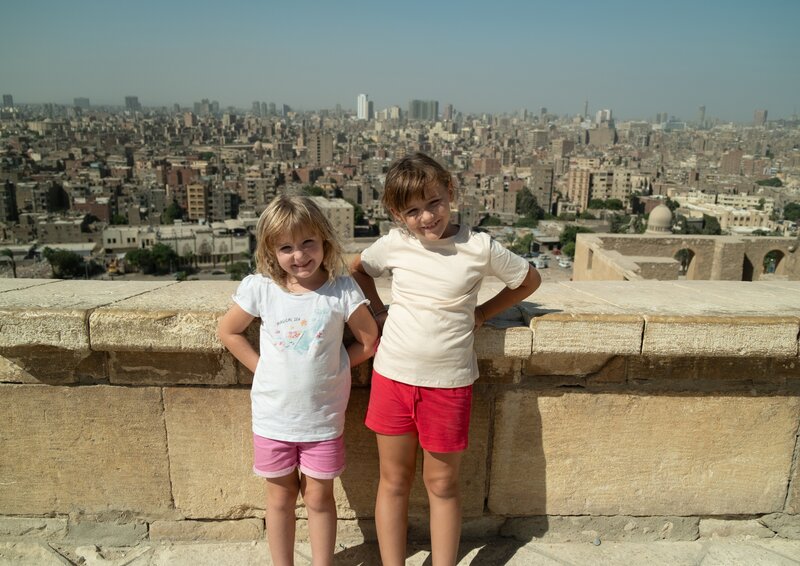 Lilly und Mia vor der Stadtkulisse von Kairo. – Bild: KiKA/​Filip Jacobson