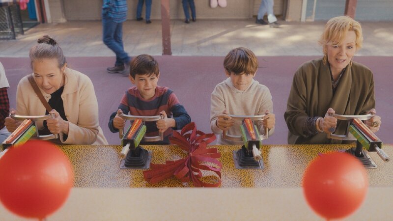 Deborah (Jean Smart, r.) lädt ihre alte Comedy-Kollegin Susan (Harriet Sansom Harris, l.) und deren zwei Enkel Mason (Henry Samiri, 2.v.l.) und Keller (Elaye Handal, 2.v.r.) zum Jahrmarkt ein. Doch auch beim Schießstand kann Deborah nicht anders, als sich erneut mit Susan zu messen – ein impulsiver Moment, der alte Wunden aufreißt. – Bild: ZDF und Karen Ballard