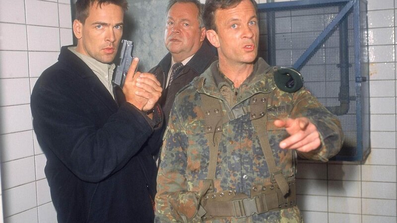 Der Soldat Heinz ist durchgedreht und bedroht die Kommissare (li. Wolfgang Krewe, Mi. Wolfgang Bathke) mit seinem Schnellfeuergewehr. Oberfeldwebel Walter (Thomas Anzenhofer) versucht die heikle Situation zu beenden … – Bild: RTL Deutschland
