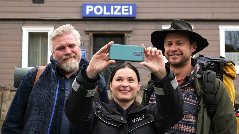 Mette (Anna Fischer) hat Frank (Aljoscha Stadelmann, li.) zum Geburtstag ein Survivalwochenende mit Heiner (Moritz Führmann, re.) geschenkt und macht zum Abschied ein Selfie. – Bild: ARD Degeto/​Kai Schulz
