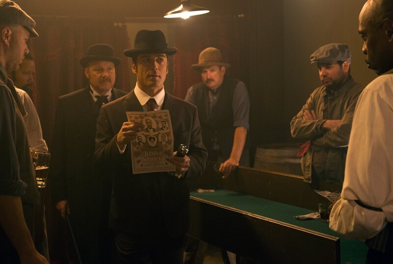 Detective Murdoch (Yannick Bisson, mi.) befragt zusammen mit Brackenreid (Thomas Craig, 3.v.l.) den Besitzer des Blind Pig zu den Jubilee Singers. – Bild: WDR/​Shaftesbury Murdoch VIII Inc