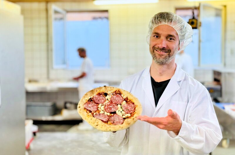 Die Pizza-Vielfalt in Deutschen Tiefkühlregalen wächst. Daniel Aßmann schaut sich die Herstellung in „Ausgerechnet – Pizza“ bei Freda in Passau an. – Bild: WDR/​Bavaria Entertainment GmbH/​Paul Bogdanski