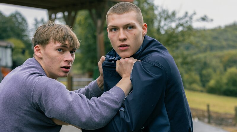 Auf dem Bauernhof: Aaron (Raphael Stojku, li.) und „Fresse“ (Beren Zint) geraten aneinander, als Fresse Michelle bemerkt. – Bild: ARD Degeto Film/​Rat Pack Filmpro /​ ARD Degeto/​Programmplanung und P