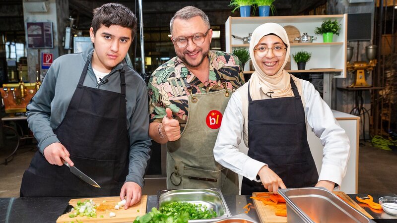 Sebastian Lege bereitet mit einem Schüler und einer Schülerin der Katharina-Henoth-Gesamtschule in seiner Foodwerkstatt eine gesunde Snackalternative zu. – Bild: ZDF und Katja Inderka