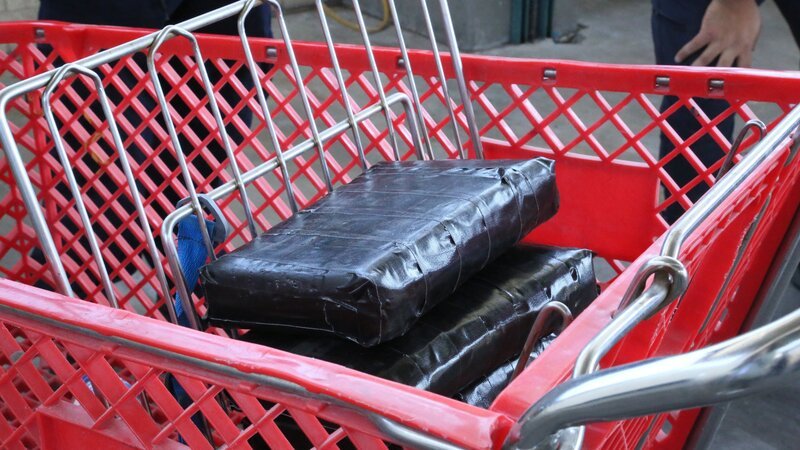 Mehrere Pakete mit mutmaßlichen Betäubungsmitteln, die im Fahrzeug eines Verdächtigen gefunden wurden, werden in einen roten Einkaufswagen gelegt und gesammelt. (National Geographic) – Bild: National Geographic /​ National Geographic