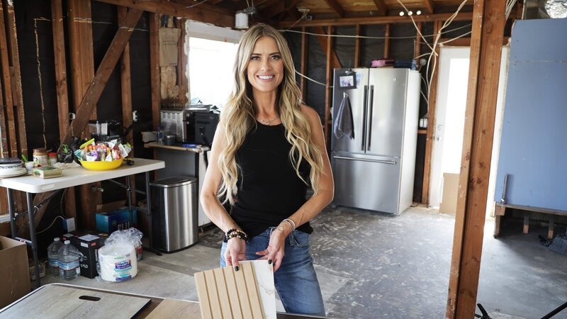 Christina Hall poses with backsplash and countertop samples in the Halbmaiers’ demolished kitchen. – Bild: Warner Bros. Discovery