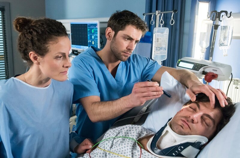 Dr. Niklas Ahrend (Roy Peter Link, Mitte) untersucht Tobias Rasch (Timur Isik, rechts). Auch seine Kollegin und Unfallgegnerin Helena Lübeck (Barbara Lanz) sieht nach ihm. – Bild: ARD/​Jens Ulrich Koch