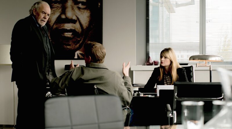 Rick Spoery (Helgi Schmid, Mitte) sucht Hilfe bei Thomas Borchert (Christian Kohlund, li.) und Dominique Kuster (Ina Paule Klink, re.). – Bild: ARD Degeto Film/​Graf Film/​Pascal Mora