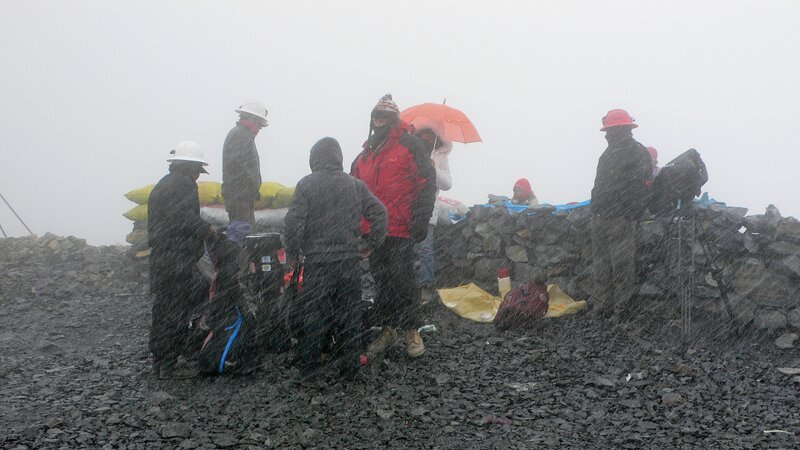 Filmteam und Goldminenarbeiter während eines überraschenden Schlechtwettereinbruchs vor der Mine Peru (5450m. über den Meeresspiegel). – Bild: ORF/Cosmos Fa Filmteam und Goldminenarbeiter während eines überraschenden Schlechtwettereinbruchs vor der Mine Peru (5450m. über den Meeresspiegel). – Bild: ORF/Cosmos Fa