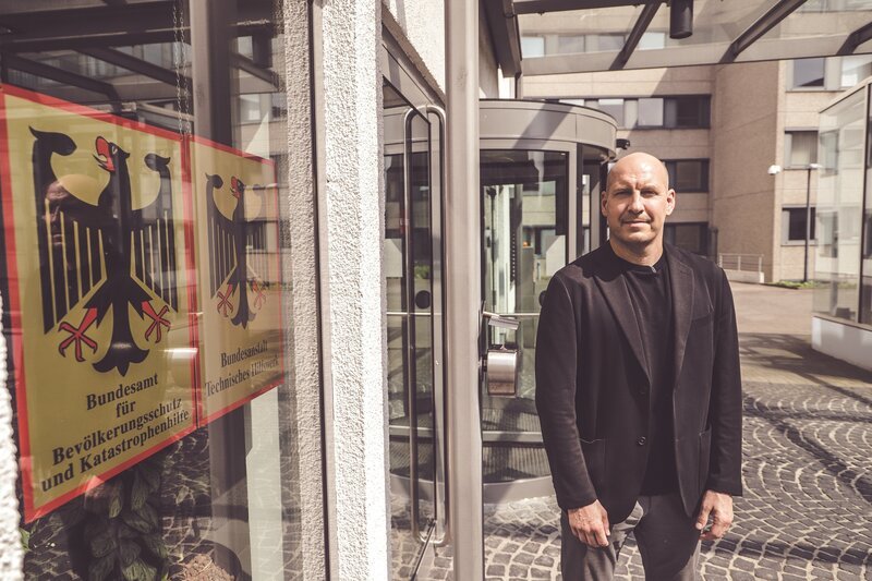 Reporter Sebastian Galle vor dem Bundesamt für Bevölkerungsschutz und Katastrophenhilfe in Bonn. – Bild: Lars Schwellnus /​ ZDF