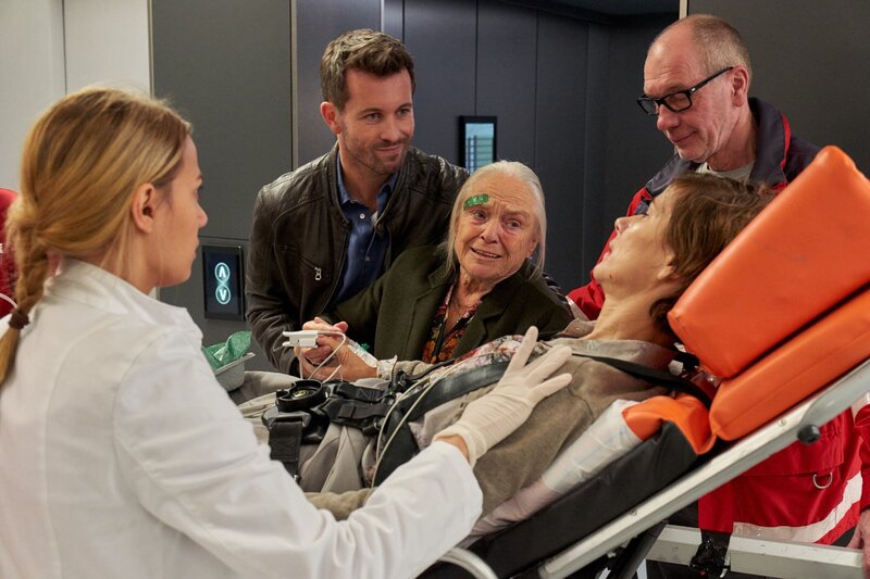 Alex Rode (Jan Hartmann, 2.v.l.) kommt mit Erika Gronau (Sylvana Krappatsch, liegend) und ihrer Mutter Klara Gronau (Maria Mägdefrau) in die Notaufnahme, wo Dr. Caro Diehl (Jytte-Merle Böhrnsen, l.) sich sofort um Erika kümmert. – Bild: MG RTL D /​ Frank Dicks