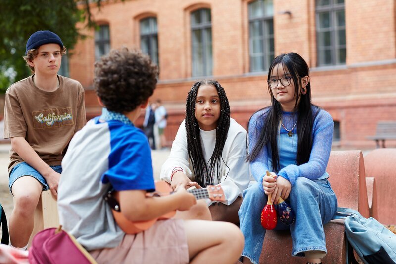 Milli (Marie Ngando Schröter) ist überrascht, dass die Band auf dem Schulhof übt. Sie bietet an, dass sie bei ihr Zuhause proben können. – Bild: ZDF/​ Studio Zentral