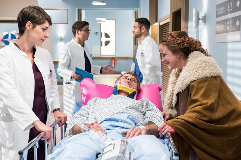 Der schwer verletzte Bernd Kaiser (Rainer Furch, M.) muss sofort operiert werden. Dass seine Freundin Bettina Bach (Bettina Kupfer, r.) ihn sehen und mit ihm sprechen will, kommt den Ärzten (Katharina Nesytowa, l., Stefan Ruppe, 2.v.l., Mike Adler, 2.v.r.) nicht so gelegen. – Bild: NDR/​ARD/​Jens Ulrich Koch