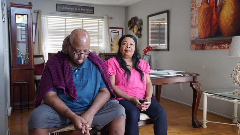 Arlin Potts stands outside looking off into the distance. He has a towel over his shoulders, and a spray bottle in his hand. The back and side of his tumor can be seen from the camera position. – Bild: Warner Bros. Discovery, Inc.