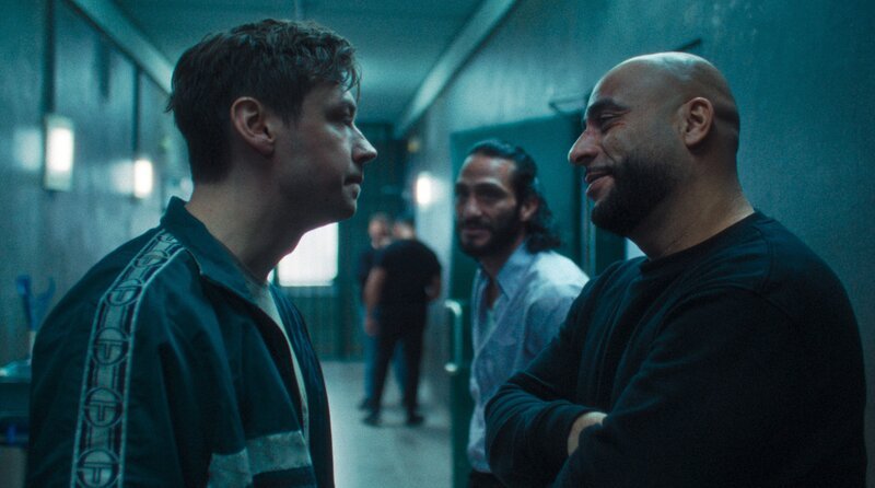 Wiktor (David Kross, li.) verkündet vor Hassan (Veysel Gelin, re.) und Sharif (Burak Yiğit, Mitte), dass er kämpfen will. – Bild: ARD Degeto Film/​Pantaleon Films GmbH/​Repro